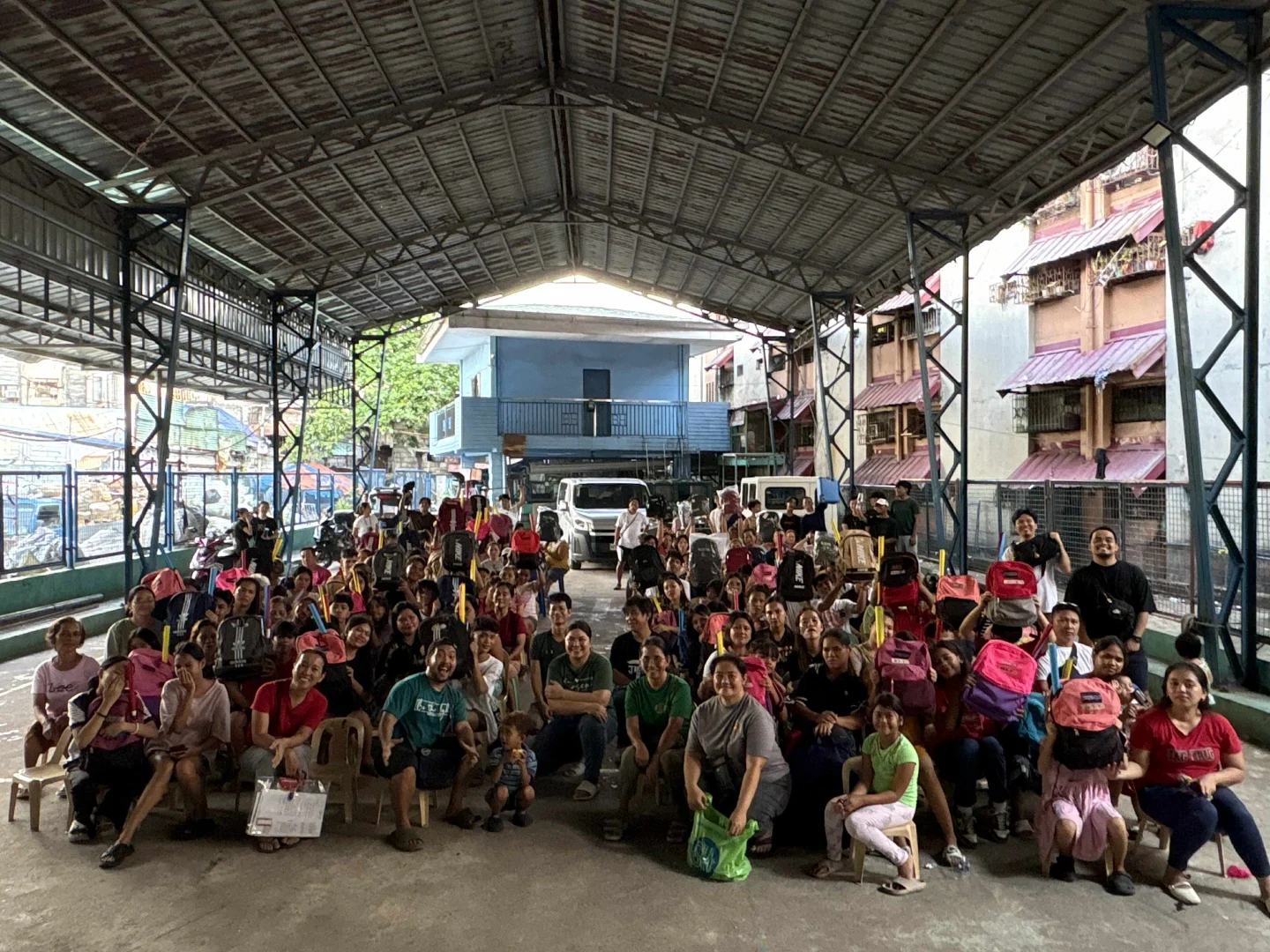 Children and families seated together on a covered basketball court