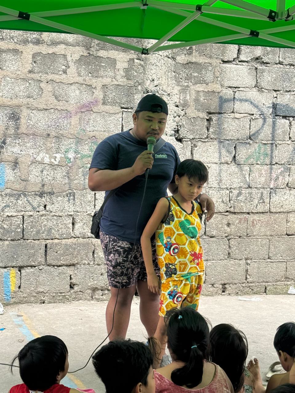 Community outreach gathering with children under a tent in Tondo